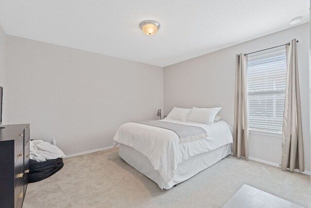 bedroom featuring light colored carpet, multiple windows, and baseboards