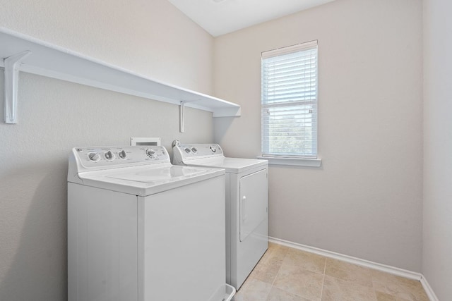 clothes washing area with washing machine and clothes dryer and baseboards