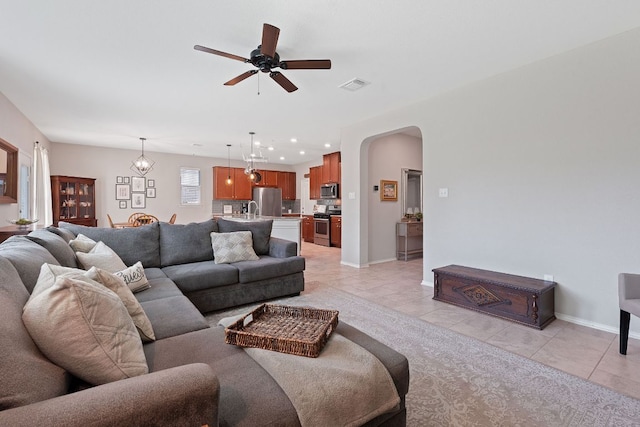 living area with light tile patterned floors, ceiling fan, arched walkways, baseboards, and recessed lighting