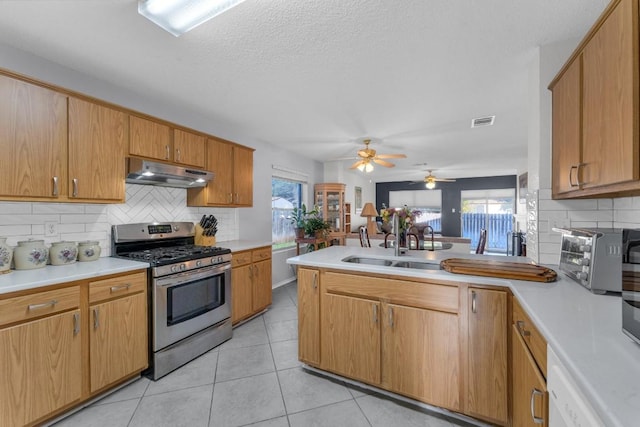 302 Debora Dr, Georgetown, TX 78628 - kitchen with gas stove, under cabinet range hood, a peninsula, decorative backsplash, and light countertops