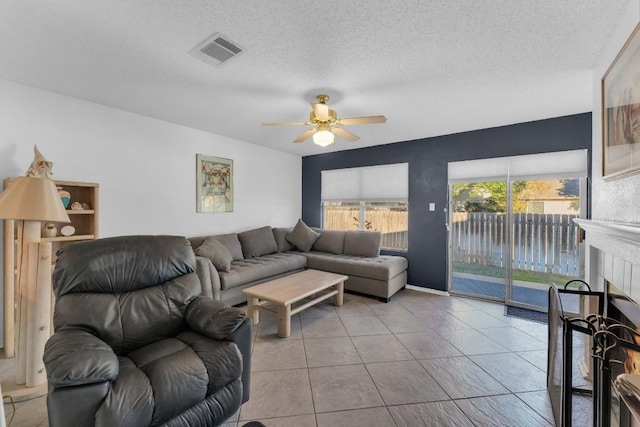 302 Debora Dr, Georgetown, TX 78628 - tiled living area featuring a ceiling fan, a tiled fireplace, and a textured ceiling