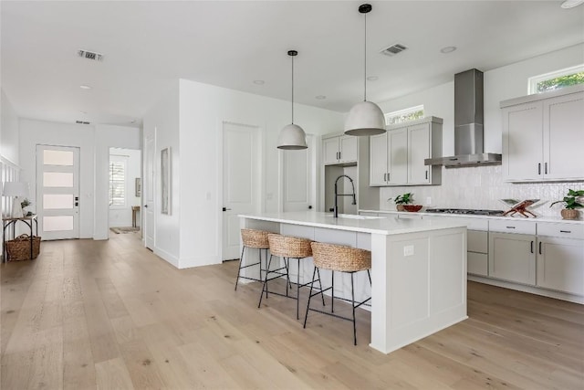 1809 Pasadena Dr, Austin, TX 78757 - kitchen with wall chimney exhaust hood, a sink, decorative backsplash, gas cooktop, and light wood finished floors