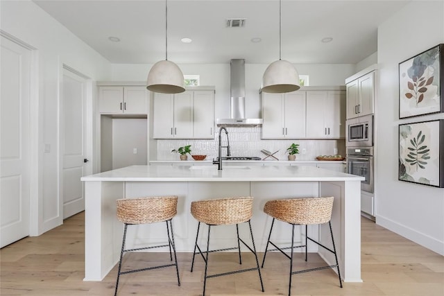 1809 Pasadena Dr, Austin, TX 78757 - kitchen with wall chimney range hood, appliances with stainless steel finishes, decorative backsplash, light countertops, and a breakfast bar area