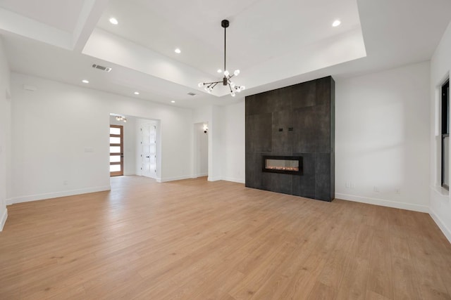 310 Apache Tears, Horseshoe Bay, TX 78657 - unfurnished living room featuring light wood-style floors, recessed lighting, a chandelier, a fireplace, and a tray ceiling