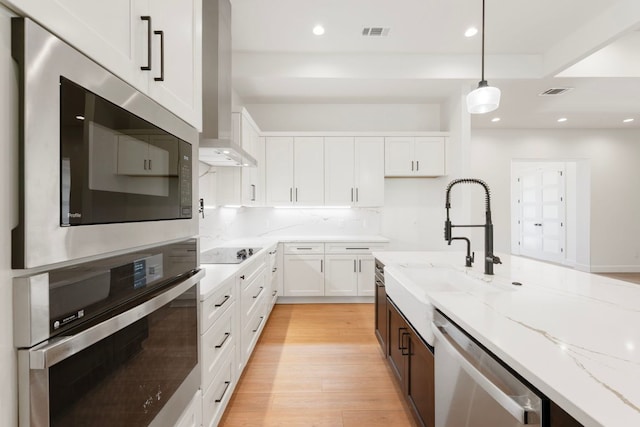 310 Apache Tears, Horseshoe Bay, TX 78657 - kitchen with stainless steel appliances, a sink, wall chimney range hood, light stone counters, and white cabinetry
