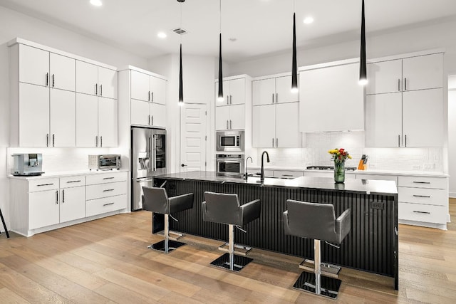 3417 Prairie Heights Dr, Leander, TX 78641 - kitchen featuring appliances with stainless steel finishes, a sink, a breakfast bar area, decorative light fixtures, and decorative backsplash
