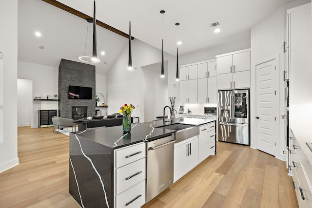 3417 Prairie Heights Dr, Leander, TX 78641 - kitchen featuring stainless steel appliances, a sink, high vaulted ceiling, a center island with sink, and light wood-style floors
