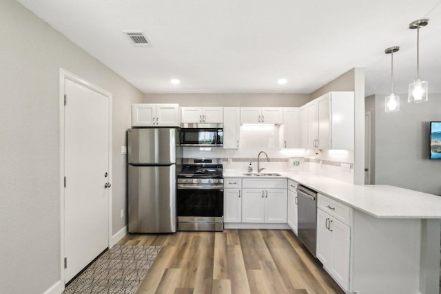 302 Martin Luther King St, Georgetown, TX 78626 - kitchen featuring stainless steel appliances, a peninsula, light countertops, light wood-type flooring, and white cabinets
