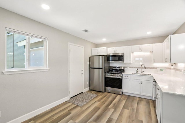 302 Martin Luther King St, Georgetown, TX 78626 - kitchen featuring appliances with stainless steel finishes, a sink, light countertops, white cabinetry, and light wood finished floors