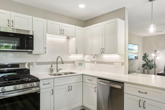 302 Martin Luther King St, Georgetown, TX 78626 - kitchen featuring stainless steel appliances, white cabinetry, tasteful backsplash, and a peninsula
