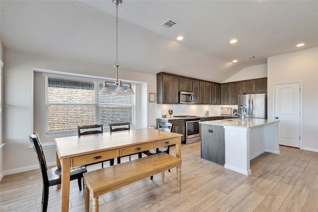 131 Mount Ellen St, Hutto, TX 78634 - kitchen featuring stainless steel appliances, dark brown cabinets, lofted ceiling, light wood finished floors, and pendant lighting