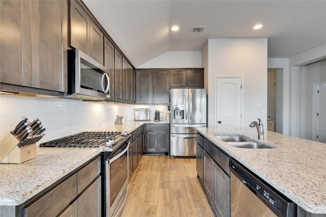 131 Mount Ellen St, Hutto, TX 78634 - kitchen featuring appliances with stainless steel finishes, a sink, light wood-style floors, dark brown cabinets, and light stone countertops