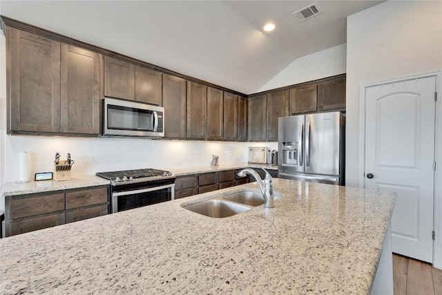 131 Mount Ellen St, Hutto, TX 78634 - kitchen with stainless steel appliances, a sink, lofted ceiling, dark brown cabinetry, and backsplash