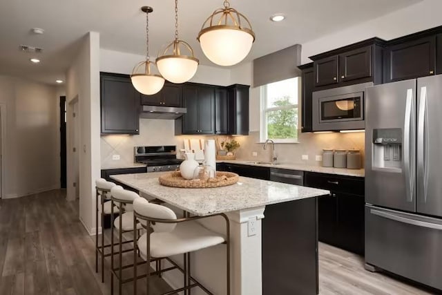 123 Crossbar St, Georgetown, TX 78633 - kitchen featuring appliances with stainless steel finishes, a center island, a sink, a breakfast bar, and backsplash