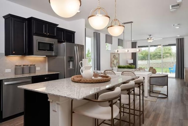 123 Crossbar St, Georgetown, TX 78633 - kitchen with stainless steel appliances, dark cabinets, open floor plan, a center island, and ceiling fan