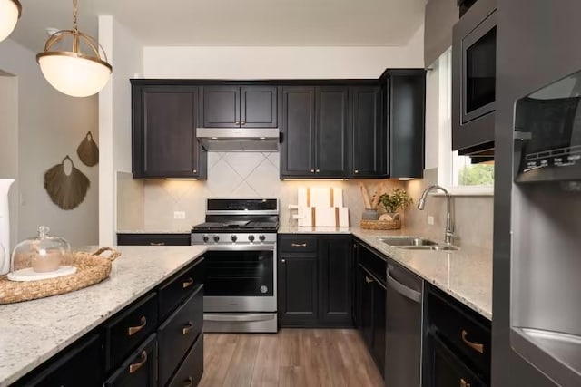 123 Crossbar St, Georgetown, TX 78633 - kitchen featuring stainless steel appliances, a sink, under cabinet range hood, light stone countertops, and decorative backsplash
