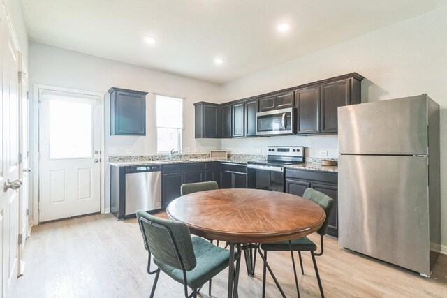 533 Peony Ct, Jarrell, TX 76537 - kitchen featuring appliances with stainless steel finishes, light wood-style floors, a sink, recessed lighting, and light stone counters