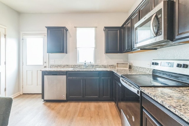 533 Peony Ct, Jarrell, TX 76537 - kitchen with stainless steel appliances, a sink, light wood-type flooring, and light stone countertops