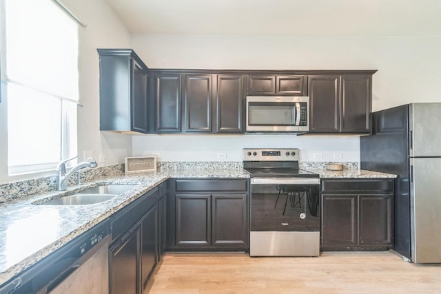533 Peony Ct, Jarrell, TX 76537 - kitchen featuring appliances with stainless steel finishes, a sink, light stone counters, and light wood-style flooring