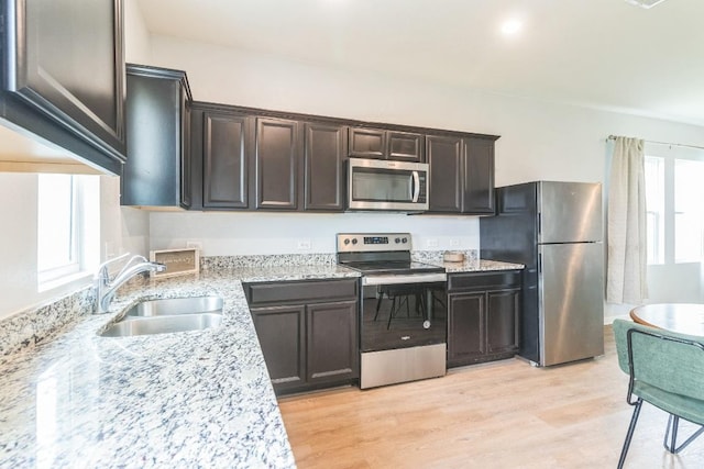 533 Peony Ct, Jarrell, TX 76537 - kitchen featuring appliances with stainless steel finishes, a sink, light wood-type flooring, light stone countertops, and dark brown cabinets