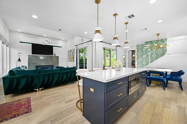2002 E 8th St, Austin, TX 78702 - kitchen featuring stainless steel microwave, light wood-type flooring, a fireplace, open floor plan, and light countertops