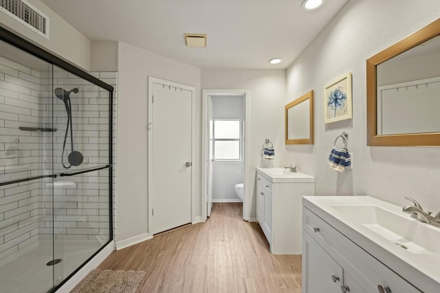 12308 Wycliff Ln, Austin, TX 78727 - bathroom with a stall shower, wood finished floors, two vanities, and recessed lighting