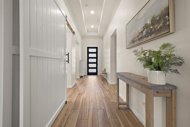 doorway to outside with a barn door, light wood-style floors, baseboards, and recessed lighting