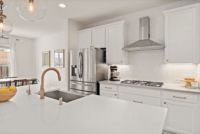kitchen with wall chimney exhaust hood, stainless steel appliances, a sink, decorative backsplash, and white cabinetry