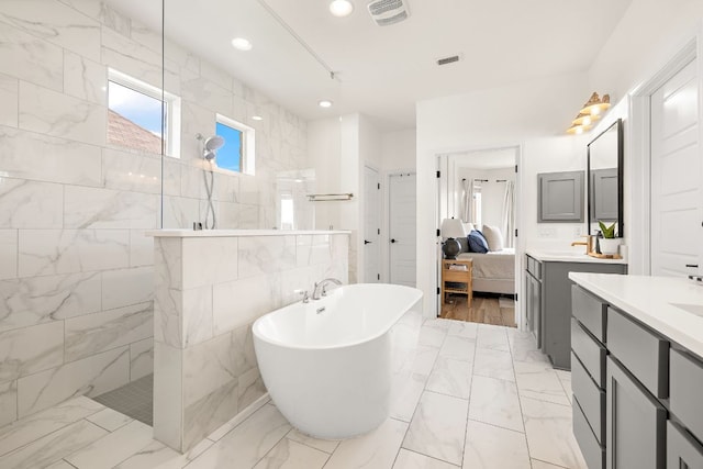 ensuite bathroom with a walk in shower, vanity, marble look tile flooring, a freestanding bath, and recessed lighting