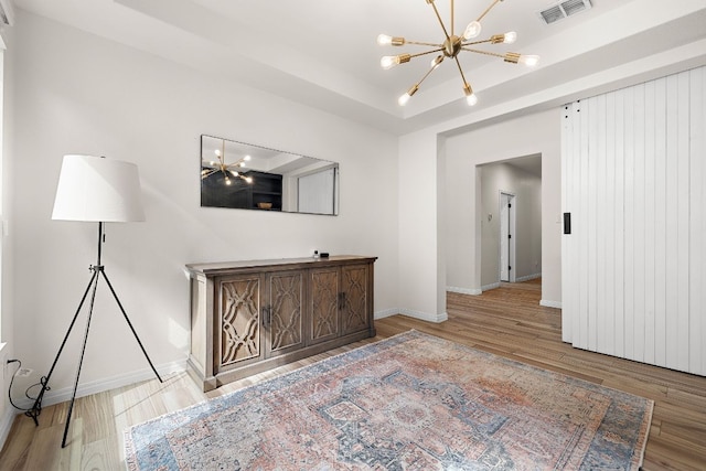 unfurnished room with a chandelier, wood finished floors, baseboards, and a tray ceiling
