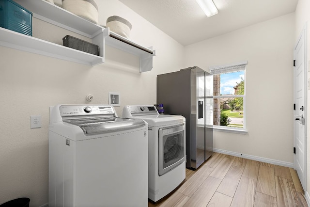 laundry room featuring washer and clothes dryer, baseboards, and light wood-type flooring