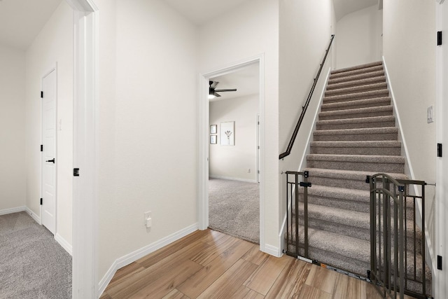 stairs featuring ceiling fan, wood finished floors, and baseboards