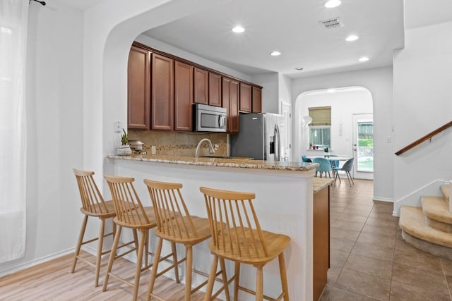 1121 Salem Park Ct, Austin, TX 78745 - kitchen with stainless steel appliances, arched walkways, backsplash, a breakfast bar area, and recessed lighting