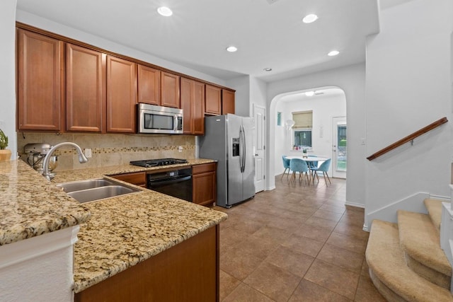 1121 Salem Park Ct, Austin, TX 78745 - kitchen featuring stainless steel appliances, a sink, arched walkways, light stone counters, and recessed lighting