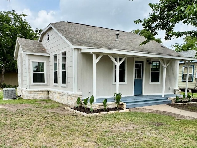 713 N Polk St, Giddings, TX 78942 - view of front of property with covered porch, a front yard, roof with shingles, and central AC unit
