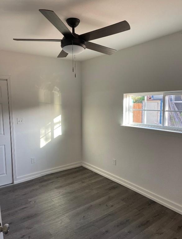 713 N Polk St, Giddings, TX 78942 - empty room with a ceiling fan, baseboards, and dark wood-style flooring