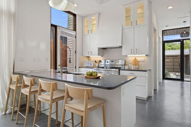 607 Terrell Hill Dr Unit B, Austin, TX 78704 - kitchen featuring stainless steel range with gas cooktop, dark countertops, backsplash, a kitchen breakfast bar, and white cabinets