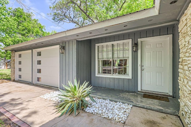 906 Hermitage Dr, Austin, TX 78753 - doorway to property with board and batten siding, a garage, driveway, and covered porch