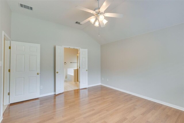 unfurnished bedroom featuring vaulted ceiling, light wood-style flooring, baseboards, connected bathroom, and ceiling fan