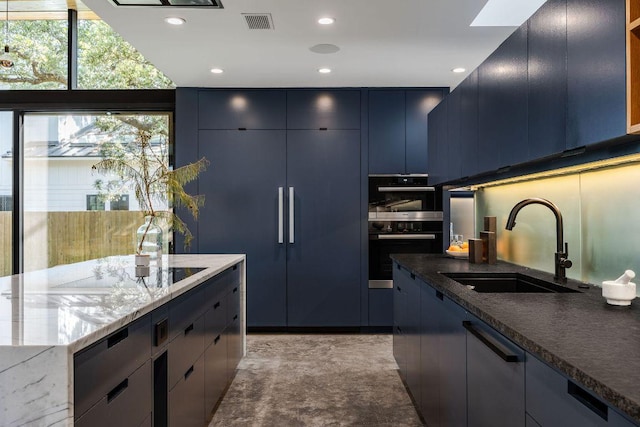 kitchen with a sink, dark stone countertops, plenty of natural light, blue cabinetry, and recessed lighting
