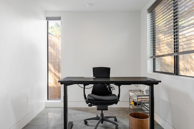 office space with concrete floors and baseboards