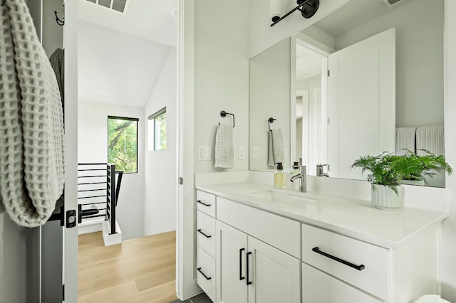 bathroom with wood finished floors, vanity, and lofted ceiling