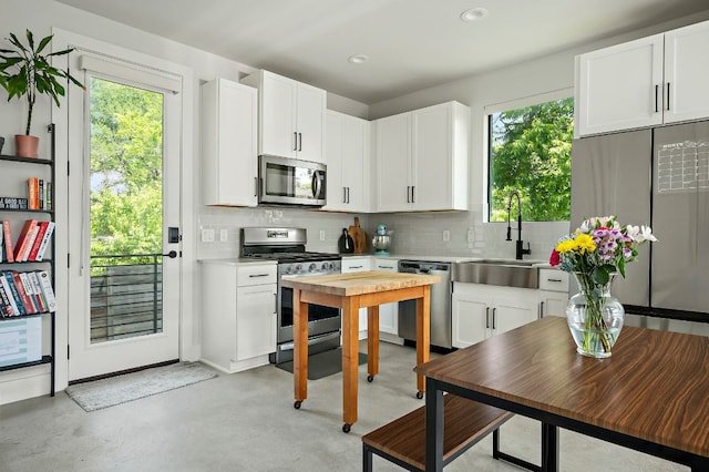 1405 Perez St Unit 2, Austin, TX 78721 - kitchen featuring appliances with stainless steel finishes, light countertops, decorative backsplash, white cabinetry, and finished concrete floors