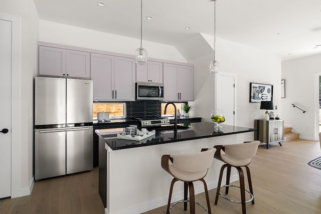 517 Tillery St Unit 1, Austin, TX 78702 - kitchen featuring appliances with stainless steel finishes, dark countertops, light wood-style flooring, decorative backsplash, and pendant lighting