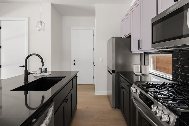 517 Tillery St Unit 1, Austin, TX 78702 - kitchen featuring stainless steel appliances, light wood finished floors, dark stone countertops, and decorative light fixtures