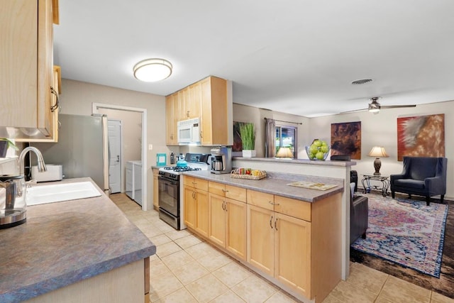 8017 Gault St, Austin, TX 78757 - kitchen featuring white microwave, gas stove, light brown cabinets, and washing machine and dryer