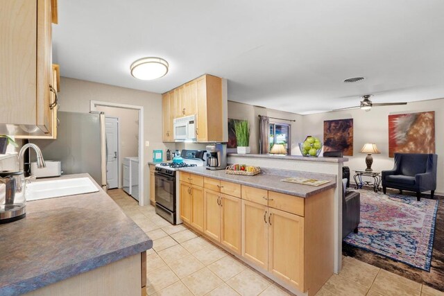 8017 Gault St, Austin, TX 78757 - kitchen with white microwave, light brown cabinetry, gas range, and washer and dryer