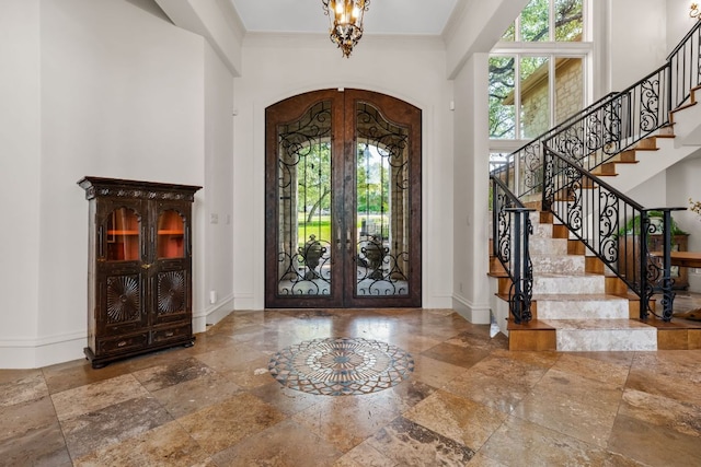 entryway featuring stone tile flooring, arched walkways, plenty of natural light, crown molding, and a towering ceiling