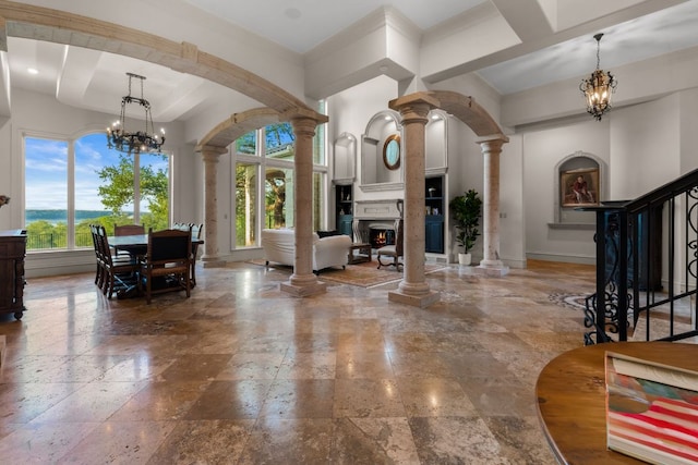 401 Brooks Hollow Rd, Lakeway, TX 78734 - entryway with ornate columns, a chandelier, stone tile floors, a lit fireplace, and baseboards