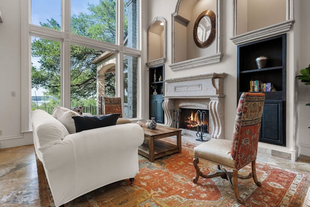 living area with a towering ceiling, a premium fireplace, and plenty of natural light